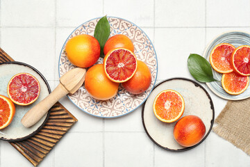 Plates with tasty blood oranges on tile background