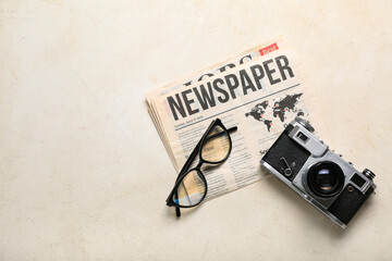 Newspaper with eyeglasses and photo camera on white background