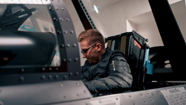 a young guy sits in a flight simulator of a military plane is worried before the start of a virtual flight of entertainment