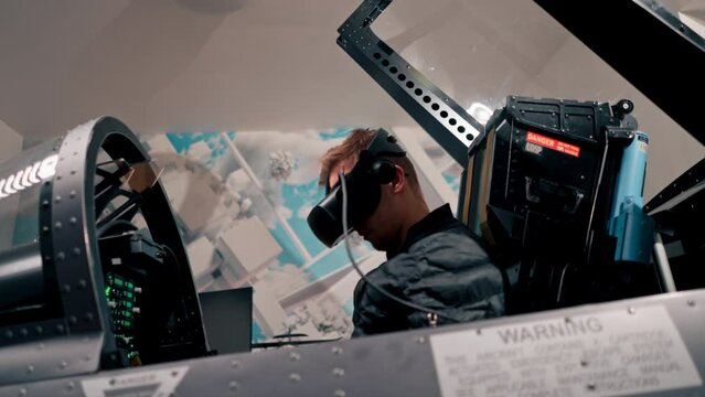 guy sitting in flight simulator of military plane wearing virtual reality glasses during flight entertainment