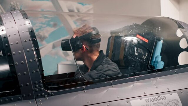 guy sitting in flight simulator of military plane wearing virtual reality glasses during flight entertainment