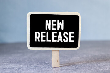 Wooden tag written new release over blue background