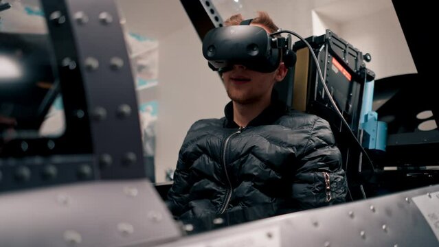 guy sitting in flight simulator of military plane wearing virtual reality glasses during flight entertainment