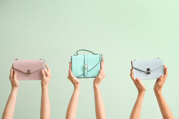 Many female hands holding different stylish bags on pale green background - Powered by Adobe