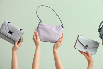 Many female hands holding different stylish bags on pale green background