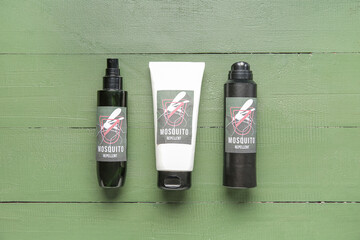 Mosquito repellent sprays and cream on green wooden background