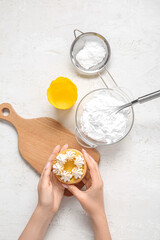 Female confectioner with tasty cake and ingredients on white background