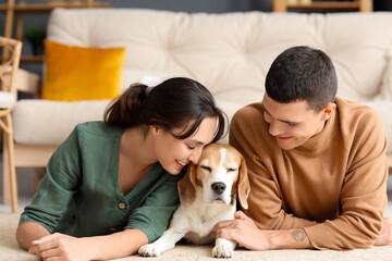 Young couple with cute Beagle dog at home