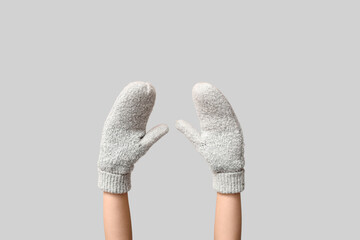 Hands in warm mittens on grey background
