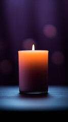 A lit candle with a flame against violet background with defocused lights