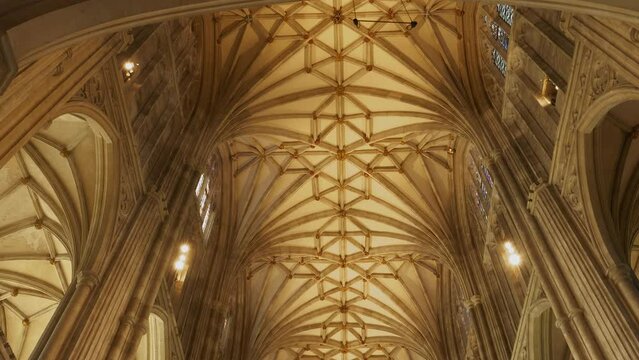 LOW ANGLE VIEW: A stunning view of the Gothic arches on high ceiling of the nave. Beautiful architectural details in every corner of Canterbury Cathedral. Stunning religious and historical monument.