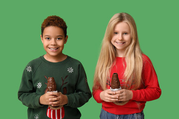 Cute little children with chocolate Santa Claus on green background