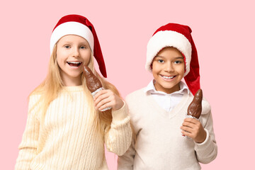 Cute little children with chocolate Santa Claus on pink background