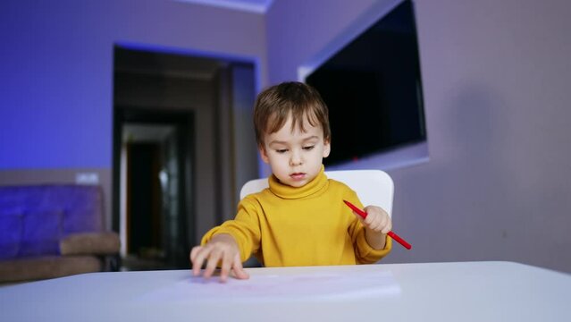 Lovely baby boy with dark hair drawing with felt pen. Little cute toddler doing art.