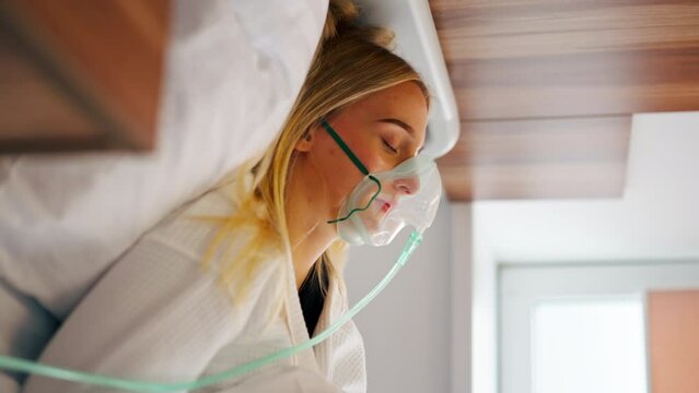 Close-up shot of a girl lying in hospital room wearing an oxygen mask to maintain breathing during illness