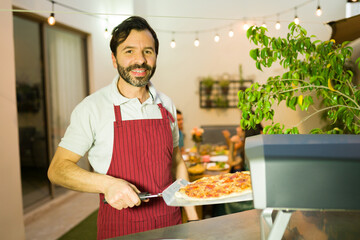 Portrait of a cheerful man baking pizza for friends for a social gathering