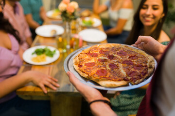 Rear view of a man hosting pizza dinner for his friends