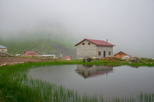 View of a rustic house reflected in a lake on a foggy Plateau.