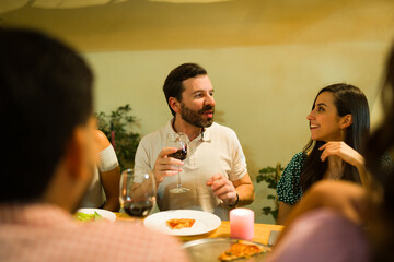 Cheerful couple talking during dinner with their friends