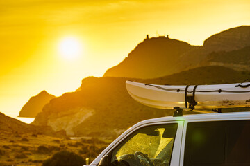 Canoe on top roof of car at sunset - obrazy, fototapety, plakaty