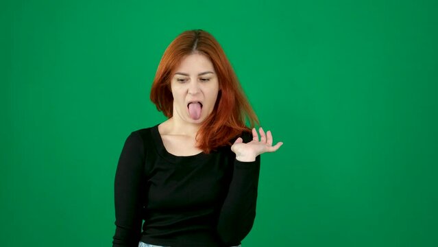 disgust dissatisfied facial expression stick out tongue gagging Reflex woman with red hair distorts her face with a grimace negative emotions smile at the end on a green background person