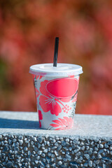 A beautiful disposable glass with a red pattern on a background of red leaves.