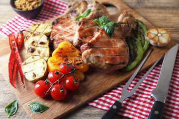 Delicious grilled meat and vegetables served on wooden table, closeup