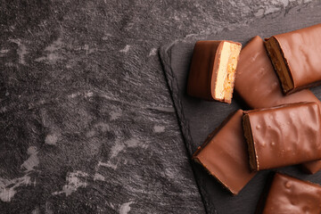 Tasty chocolate bars with nougat on gray textured table, top view. Space for text