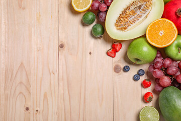 Many different fresh fruits and berries on wooden table, flat lay. Space for text
