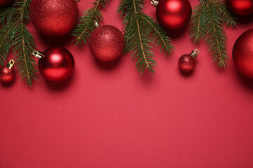 Christmas balls and fir tree branches on red background, flat lay. Space for text