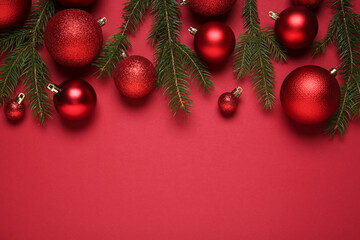 Christmas balls and fir tree branches on red background, flat lay. Space for text