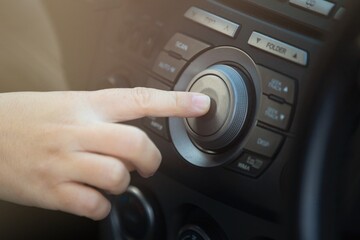Close up of woman hand pressing button on the car's dashboard. - obrazy, fototapety, plakaty