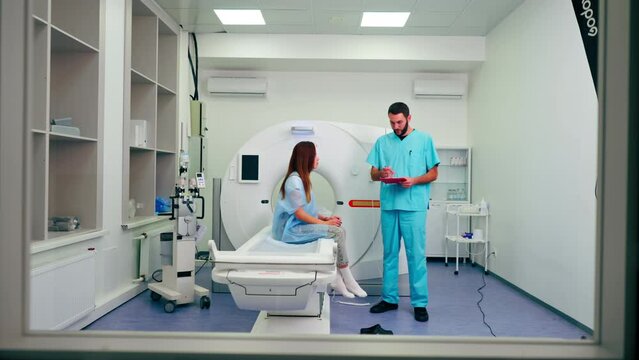 A radiologist consults a girl patient before undergoing diagnostics using an MRI machine in medical center