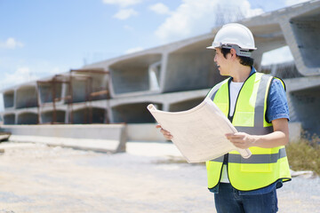 Construction engineer inspecting a segmenting bridge blueprint and construction plan at the site.