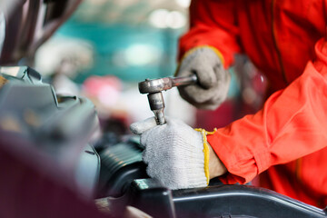 Automobile technician working in auto garage, technician holding a wrench preparing to repair...