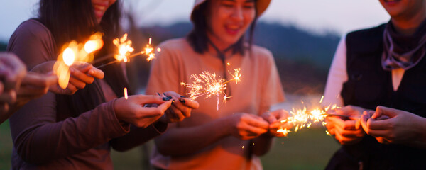 Happy men and women enjoy playing a sparklers firework in a party.