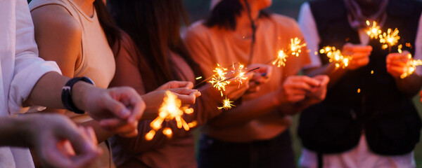 Happy men and women enjoy playing a sparklers firework in a party.