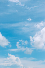 Fototapeta na wymiar Light blue pastel sky with clouds in vertical shot.