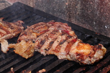 A slice of beef rib eye garnished with pepper, salt and chili peppers on the grill
