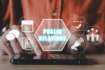 Public Relations concept, Man hand touching mobile phone on office desk with public Relations icon...