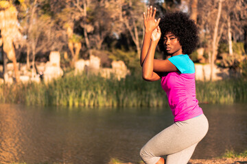 beautiful black woman with afro practicing sports and exercising in different ways, in nature on a sunny day next to a lake