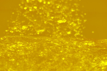 Gold water waves on the surface ripples blurred. Defocus blurred transparent gold colored clear calm water surface texture with splash and bubbles. Water waves with shining pattern texture background.