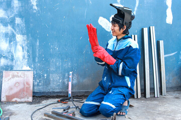 Asian worker wearing protective gloves and mask to safety before starting welding work