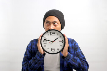 Asian man, dressed in a beanie hat and casual shirt, appears to be deep in thought and planning as...