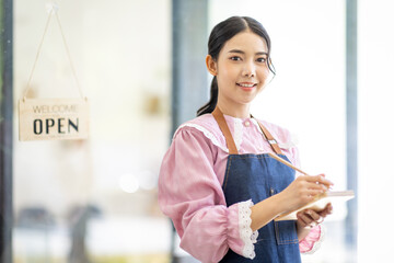 Portrait of happy waitress standing at restaurant entrance. SME entrepreneur young business asian...