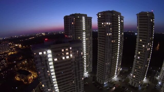 Houses of dwelling complex against cityscape at evening.