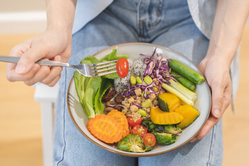 Diet concept, close up young woman hand use fork to prick tomato, fresh vegetable or green salad in plate, eat nutrition food at home, low fat to good body. Girl getting weight loss for healthy people