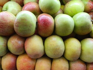 Close up pile of tasty fresh apples sold at the market as a background.