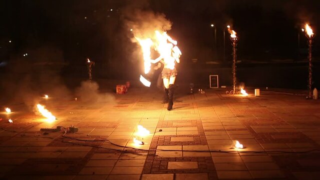 Girl moves with burning fans and boy rotates flaming pois 
