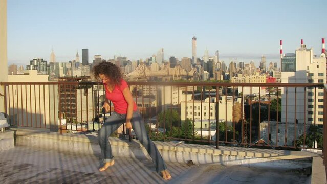 Woman dancing on roof of building, then to daughter joins.